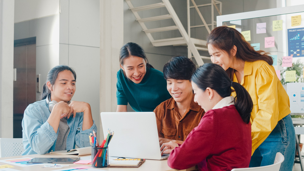 A team gathered around a laptop in a modern office